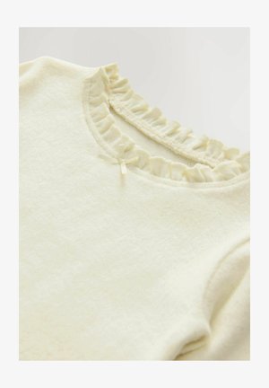 Krém színű, puha anyagból készült felső. Ráncolt nyakkivágással és kis szalag díszítéssel rendelkezik a gallérnál. Egyszerű, texturált felület.