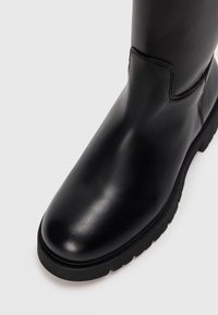 Bottines en cuir noir avec un bout arrondi, finition lisse, semelle en caoutchouc durable et peu de détails de couture sur la tige.
