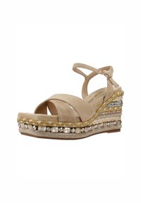 Sandale compensée beige avec des brides croisées, tige en daim texturé, semelle intermédiaire en jute tressé et perles décoratives sur le bord.