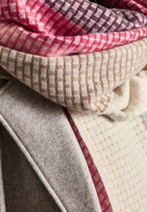 Écharpe tissée en laine douce, présentant un motif à carreaux dans des nuances variées de rose, crème et bordeaux, avec des accents texturés.