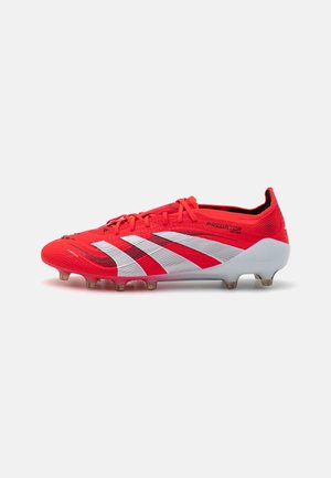 Red and white soccer cleat with a textured upper, featuring prominent three stripes design, plastic sole plate, and molded studs.