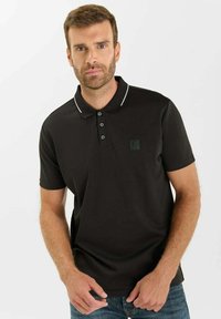 Zwarte polo met korte mouwen, witte accentstrepen op de kraag, een placket met drie knopen en een klein logo op de linkerkant van de borst.