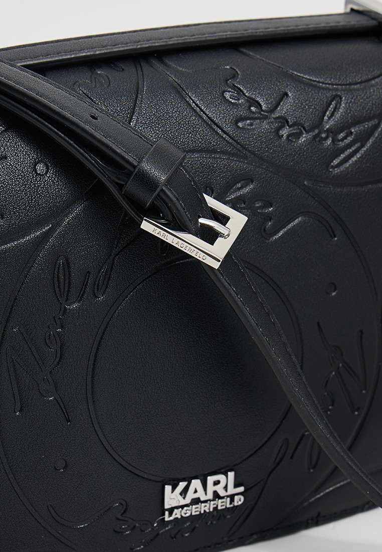 Borsa nera Karl Lagerfeld con motivo della firma in rilievo, fibbia argentata incisa con il nome del marchio e placca con logo argentata sul davanti.