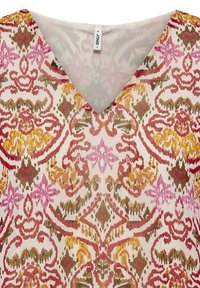 Blouse à col en V avec un motif floral dans des teintes de rose, rouge, orange et vert sur un fond crème, fabriquée en tissu léger et texturé.