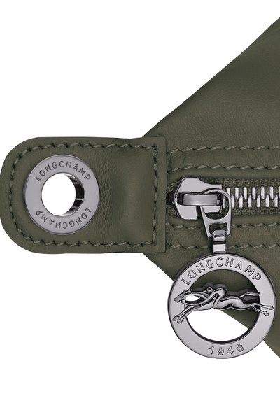 Green leather zipper pouch with silver hardware, featuring a branded charm and detailed stitching. Metallic zipper pull adds a functional accent.