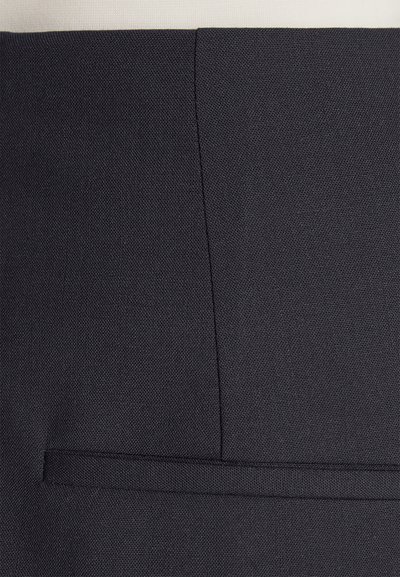 Prim-plan al unui material negru cu o textură distinctă, evidențiat printr-o cusătură și un detaliu de buzunar orizontal. Design minimalist și culoare solidă.