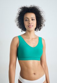 Turquoise bralette with a V-neck design, made of smooth fabric. Features wide straps and a band under the bust for support.