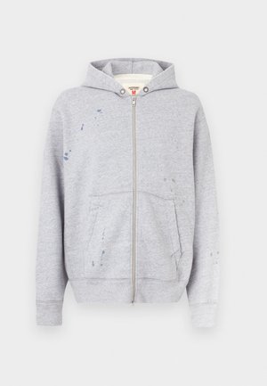 Sweat à capuche gris zippé en mélange de coton, avec capuche, poches avant et détails d'éclaboussures de peinture sur le côté gauche.