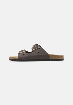 Brown two-buckle slide sandal with leather upper and cork midsole. Features textured strap accents and a flat black rubber sole.
