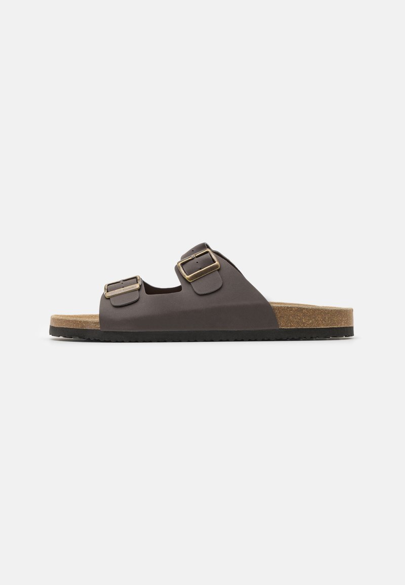 Brown two-buckle slide sandal with leather upper and cork midsole. Features textured strap accents and a flat black rubber sole.