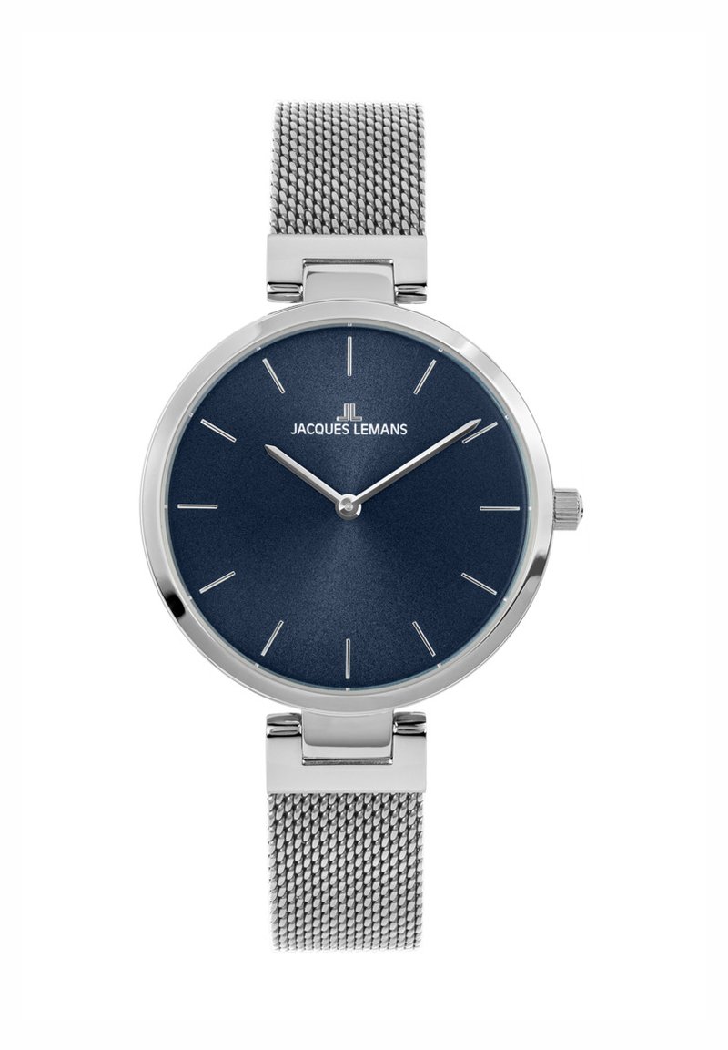 Reloj plateado redondo con un dial texturizado azul oscuro, marcadores de hora plateados y una correa de malla plateada. Presenta un diseño minimalista y hardware sencillo.