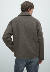 Giacca in misto lana marrone con colletto strutturato, spalle scese e vestibilità rilassata. Tessuto testurizzato dall'aspetto morbido.