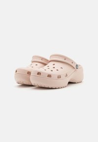 Sabots rose clair avec une pointe arrondie, des trous de ventilation, et une sangle à l'arrière, fabriqués dans un matériau lisse et flexible avec une semelle texturée.