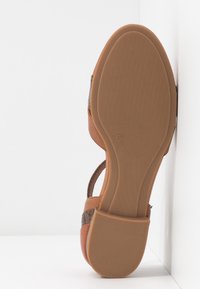 Sandale avec semelle en caoutchouc couleur fauve, grip texturé, taille 37 indiquée, et tige en matériaux mixtes dans des tons marron et beige.