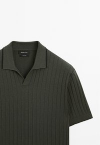 Polo vert foncé à manches courtes avec texture côtelée et col rabattable.