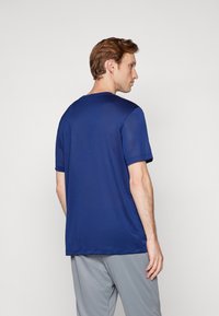 T-shirt bleu marine à manches courtes avec un col rond, fabriqué dans un tissu léger et lisse, présentant une coupe décontractée et sans motifs visibles.
