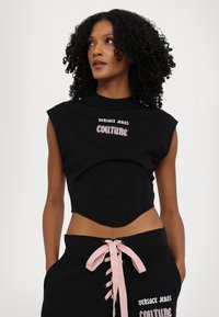 Zwart cropped top met een gestructureerde bustier en korte mouwen, voorzien van geborduurde "Versace Jeans Couture" tekst in zilver en roze.
