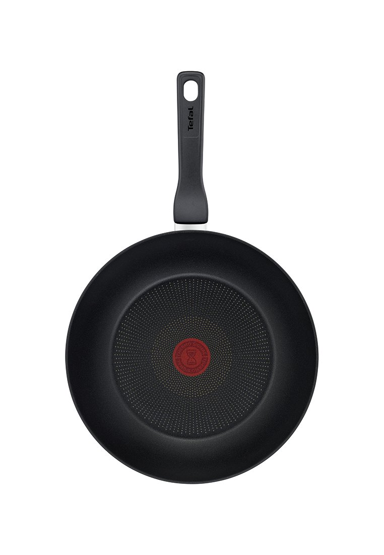 Padella nera con superficie liscia, forma rotonda e un cerchio rosso testurizzato al centro; dotata di un manico ergonomico nero.