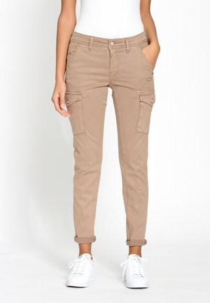 Beige cargo pants with front and side pockets, tapered leg, and rolled cuffs, made from lightweight fabric. Paired with white sneakers.