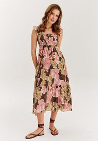 Kvetinové maxi šaty v hnedej farbe s ružovými a zelenými vzormi, so zdrhovacím živôtikom, volánovými ramienkami a poschodiajúcim lemom. Ľahký materiál.