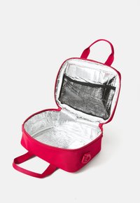 Sac à lunch isolé de couleur rose, de forme arrondie, avec fermeture zippée, doublure intérieure argentée et poche en maille noire. Deux poignées pour le transport.