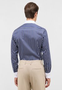 Navy-blau und weiß gestreiftes Hemd mit einer glatten Textur, klassischem Kragen und Knopfmanschetten, kombiniert mit hellbeigen Hosen.