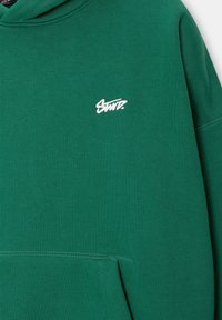 Sweat-shirt vert avec logo "Saint." brodé en style manuscrit blanc sur la poitrine et la poche avant kangourou.