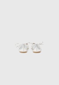 Metallic silver ballet flats with a rounded toe and a tied bow detail at the back. Smooth texture and a flexible sole.