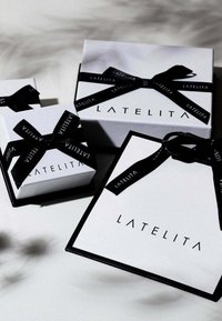 Scatole regalo bianche di varie dimensioni, con nastri neri e il nome del marchio "LATELITA" stampato in nero sui lati.