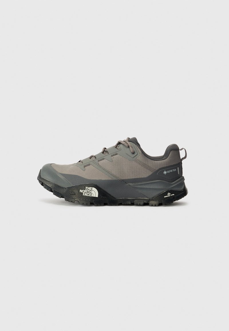 Sapatilha de trail running cinza com um cabedal texturizado, fecho de atacadores, marcação Gore-Tex e sola exterior de borracha preta. Apresenta uma entressola acolchoada e logotipo.