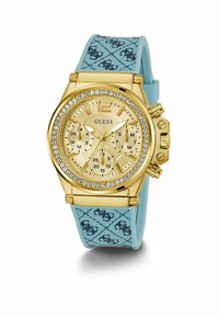 Orologio cronografo dorato con una lunetta decorata con cristalli, dotato di un bracciale in silicone blu chiaro con motivo e un quadrante dorato testurizzato.