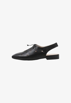 Zapato negro plano de cuero con tira trasera, punta puntiaguda, perforaciones redondas y un pequeño lazo en la parte delantera.