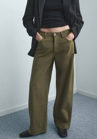 Pantalones de pierna ancha color verde oliva hechos de algodón con cintura alta, que cuentan con bolsillos delanteros, cierre con botón y detalles cosidos.