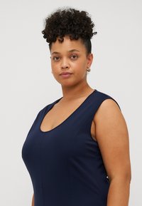 Mörkblå ärmlös klänning med rundad halsringning, slät textur och kroppsnära silhuett, med synlig sömdetaljering.