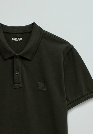 Camiseta polo de manga corta en verde oliva oscuro con dos botones, cuello y parche con el logo "SALSA JEANS" en el pecho izquierdo. Talla L, ajuste estándar.