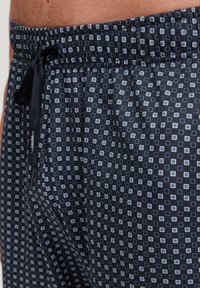 Marineblauwe shorts van een gestructureerde stof, voorzien van een geometrisch patroon van kleine witte vierkanten, elastische tailleband met een trekkoord.
