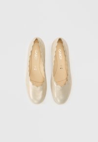 Złote metaliczne baleriny z falistymi krawędziami, gładką fakturą, wyściółką z miękką wkładką oraz logo marki na wkładce. Rozmiar 4,5.