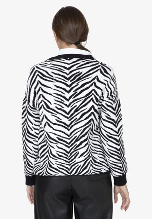 Maglione a righe zebra bianco e nero lavorato a maglia con polsini e orlo a coste, caratterizzato da una vestibilità morbida e un collare a contrasto.