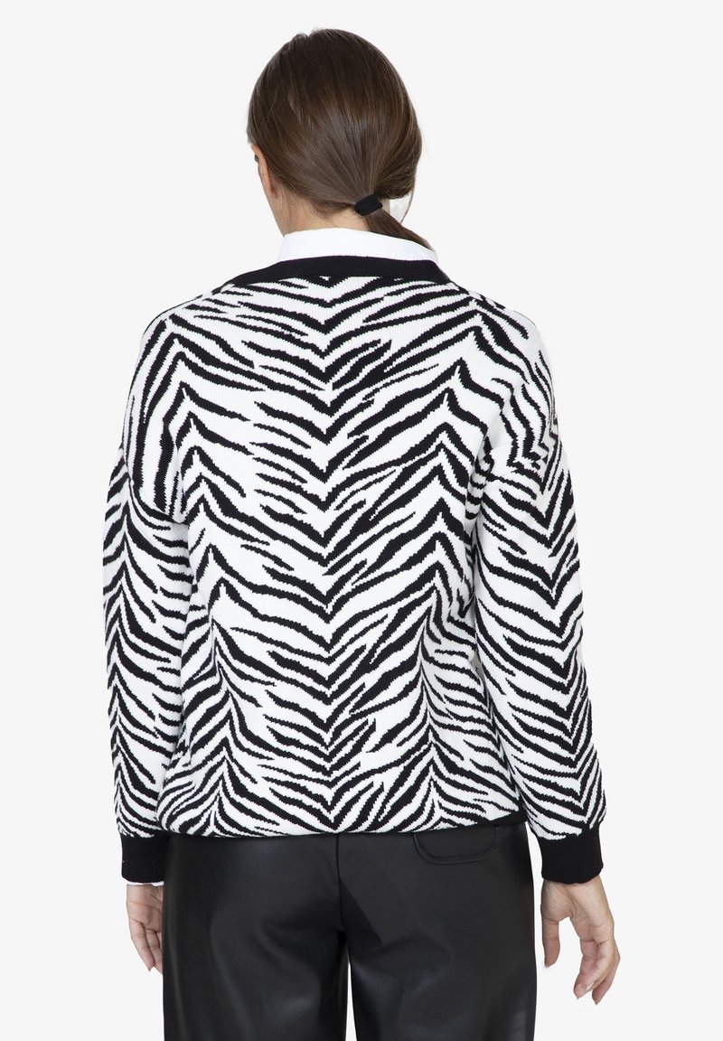 Maglione a righe zebra bianco e nero lavorato a maglia con polsini e orlo a coste, caratterizzato da una vestibilità morbida e un collare a contrasto.