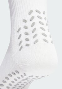 Weißer Baumwollsocken mit einem strukturierten grauen Silikongrip-Muster an der Sohle für verbesserten Halt. Glatte Strickware mit verstärktem Fersenbereich.
