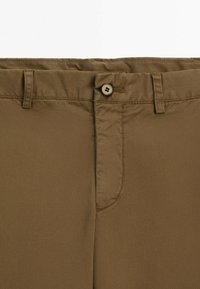 Ceinture de pantalon en coton marron avec passants de ceinture, fermeture par bouton et coutures visibles sur un fond uni.