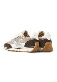 Beige and brown athletic sneakers with suede and mesh materials, featuring a textured sole, white accents, and a brand logo on the heel.