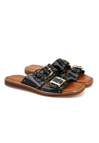Sandales à glissière en cuir noir avec deux grandes boucles décoratives, des accents cloutés et une semelle intérieure en cuir naturel sur une semelle en bois.