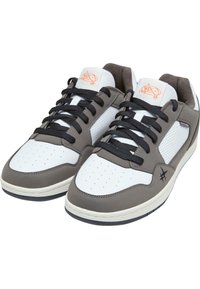 White and gray athletic sneakers with black laces, perforated toe box, orange logo on tongue, and gray suede accents on sides.