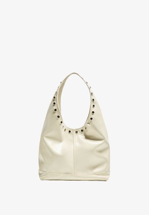 Geantă hobo din piele crem cu un umăr rotund, având decupaje circulare și accente de nuanță argintie de-a lungul marginii superioare. Textură netedă.