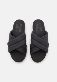 Schwarze Rutschsandalen mit einem überkreuzten Design aus strukturiertem Stoff. Die Sohle ist flach und aus einem strapazierfähigen Material gefertigt, mit einem Logo auf der Fußbett.