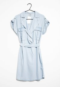 Svetle modré šambré šaty s krátkými rukávy, opaskem v pase, dvěma náprsními kapsami a klopovým límcem. Hladká textilie s volným střihem.