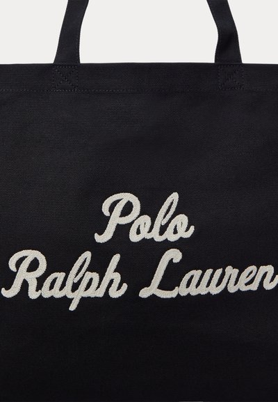 Μαύρη υφασμάτινη τσάντα tote με λευκό κεντητό κείμενο σε γραφή με πλάγιους χαρακτήρες "Polo Ralph Lauren" και μαύρες λαβές ραμμένες στο επάνω άκρο.