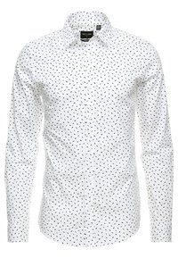 Camisa blanca de manga larga con botón, con un pequeño patrón abstracto negro, cuello extendido y estilo entallado.