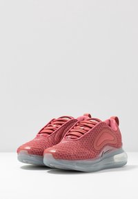 Röda sneakers med textur och hexagonmönster, elastiska skosnören, vadderad tunga och genomskinlig sula med luftkuddar.